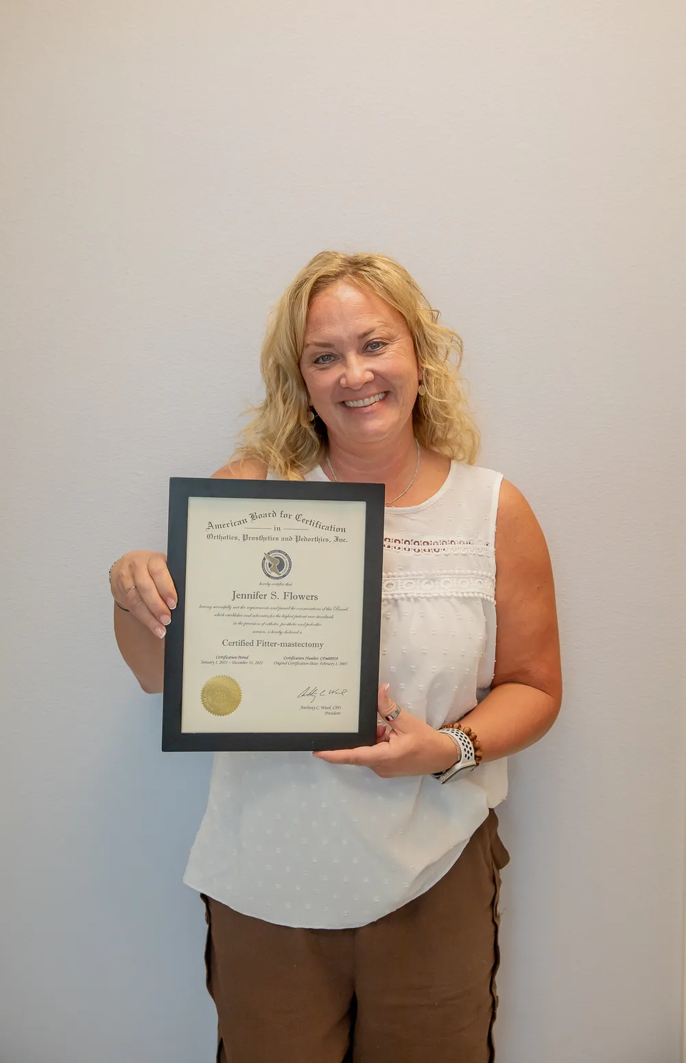 Jen Flowers holding her American Board Certified Mastectomy Fitter certificate